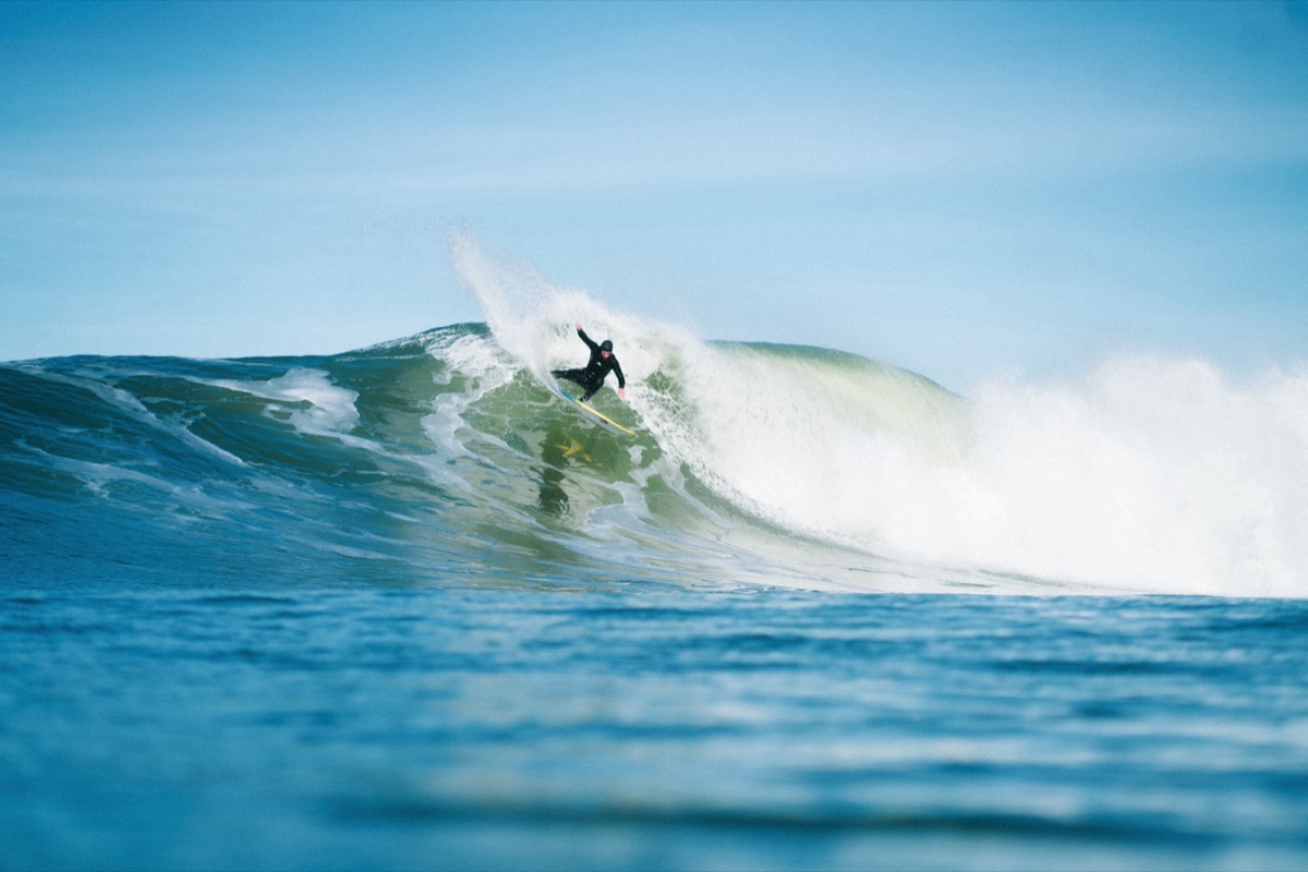 Surfeur en plein virage sur une vague verte