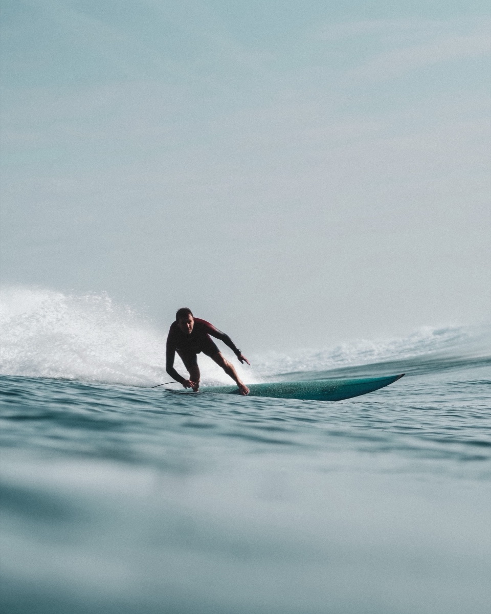 Surfeur en glisse, ciel pâle, combinaison bordeaux