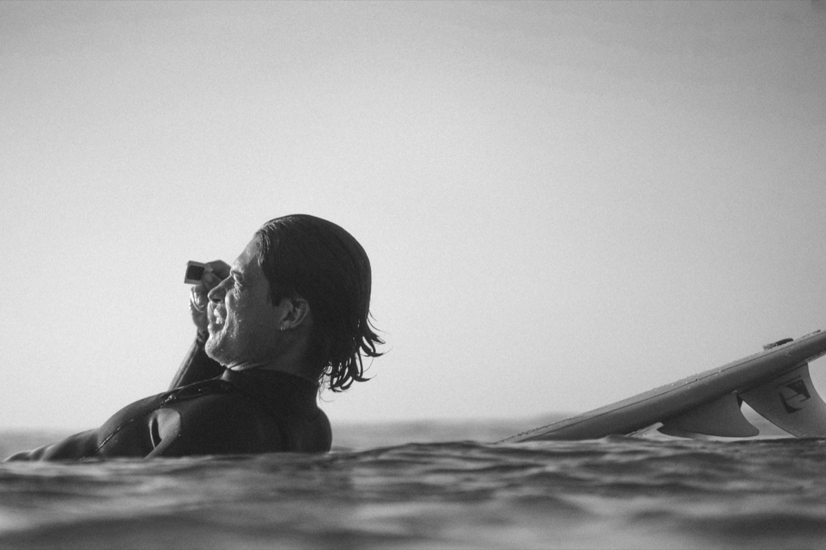 Surfeur tenant une caméra devant l'œil, profil