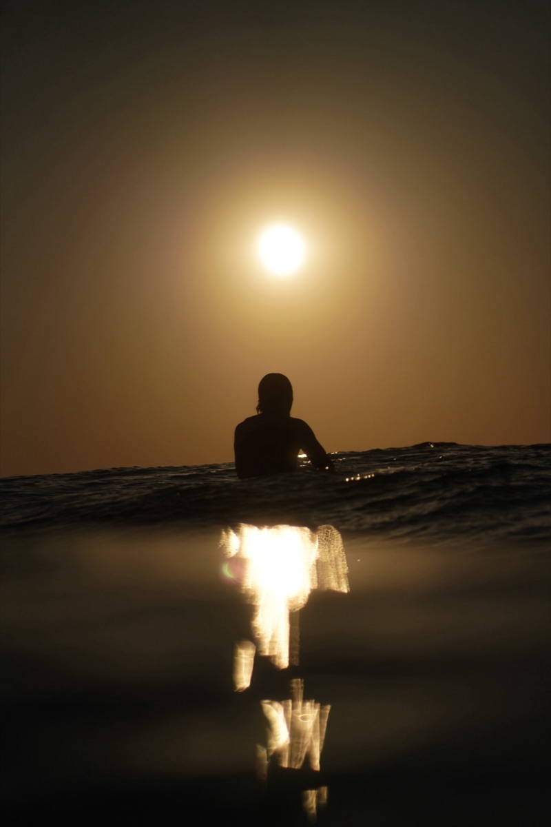 Silhouette dans l'eau face au soleil couchant