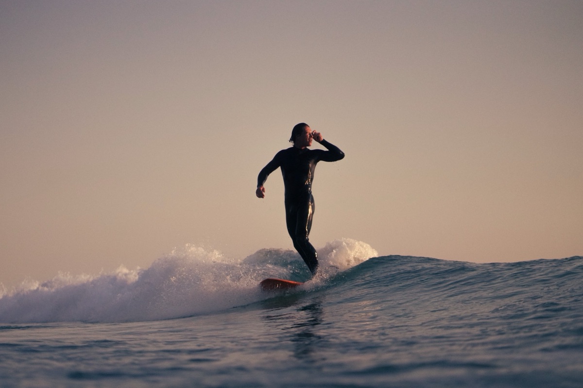 Longboardeur debout sur sa planche au coucher du soleil